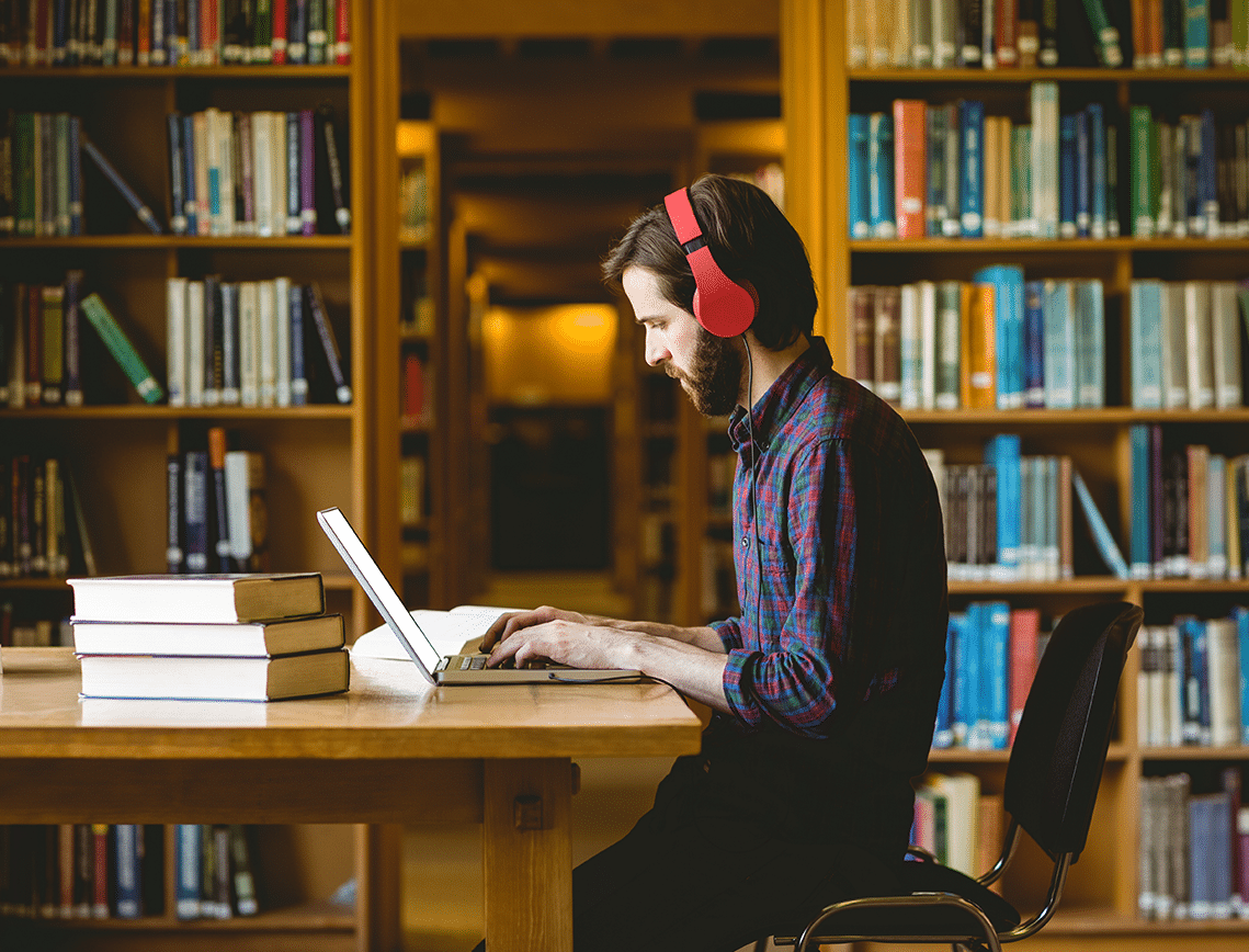 georgian-college-quote a man works on an assignment in a college library while wearing red headphones